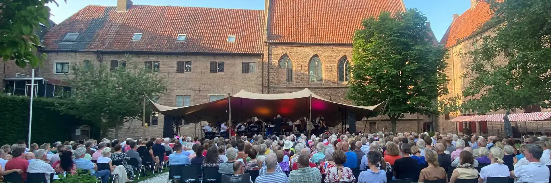 Klassiek openluchtconcert met orkest en publiek in historische Kloostertuin in Elburg